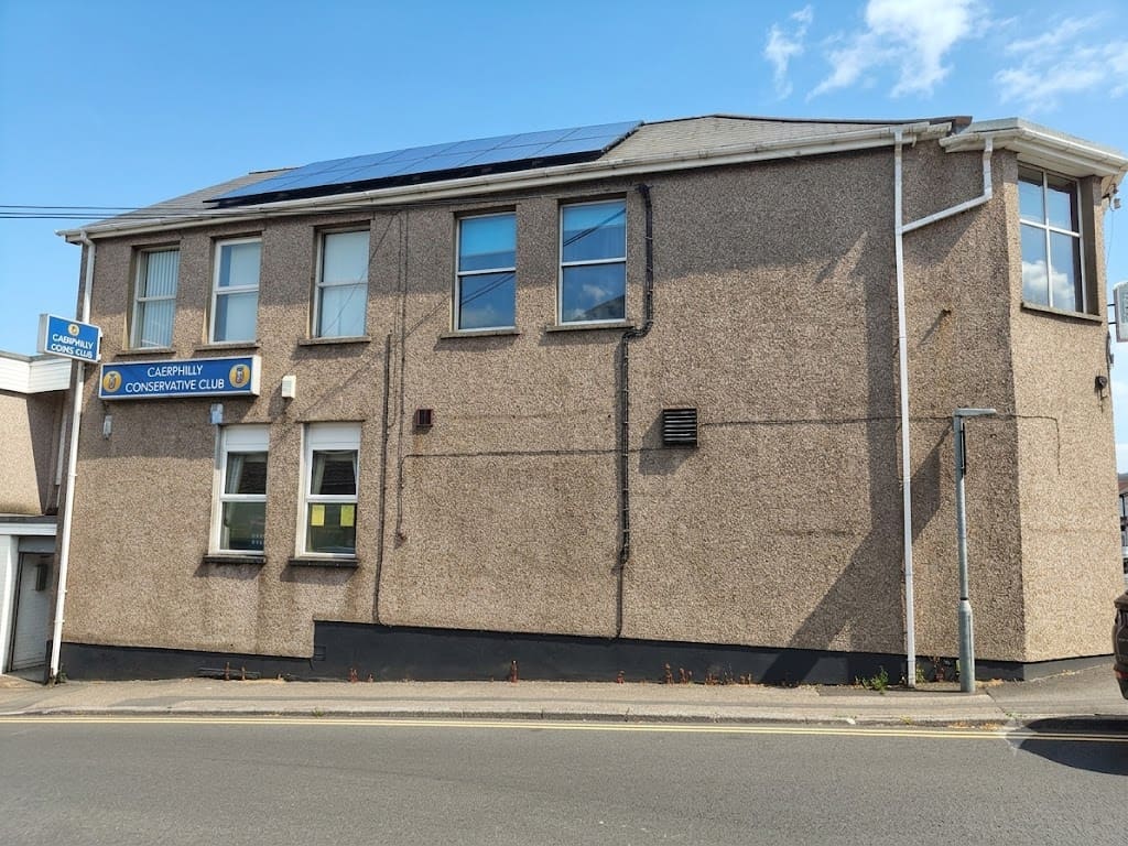The side of Caerphilly Conservative Club on Bartlett Street, a two-storey pebbledashed building with two blue signs carrying the club’s name